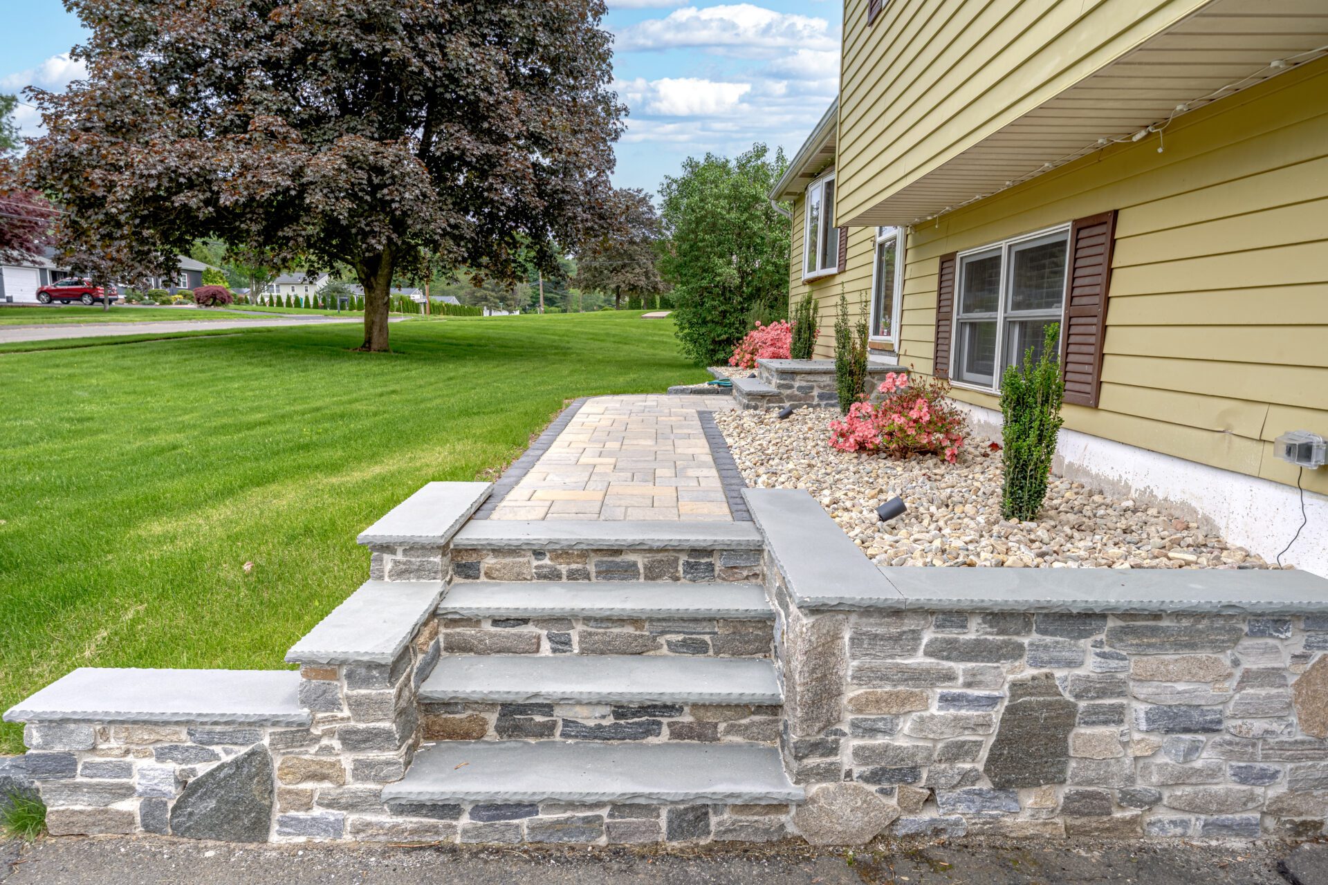 Stone walkway and shrub planting along front foundation of a Southington, CT home designed and installed by HQ Landscaping